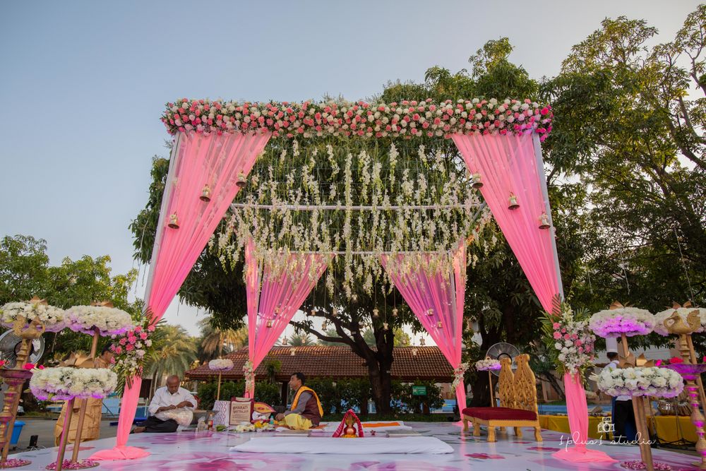 Photo of Pink draped mandap with the floral ceiling and bell hangings.