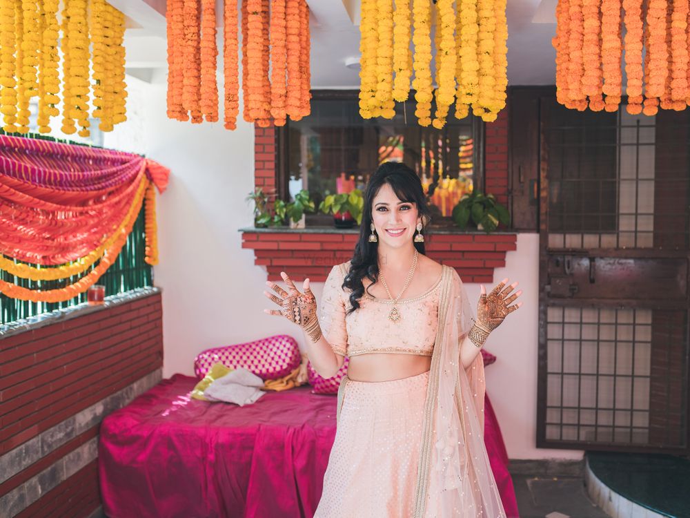 Photo of A bride to be poses in a light pink lehenga on her mehendi