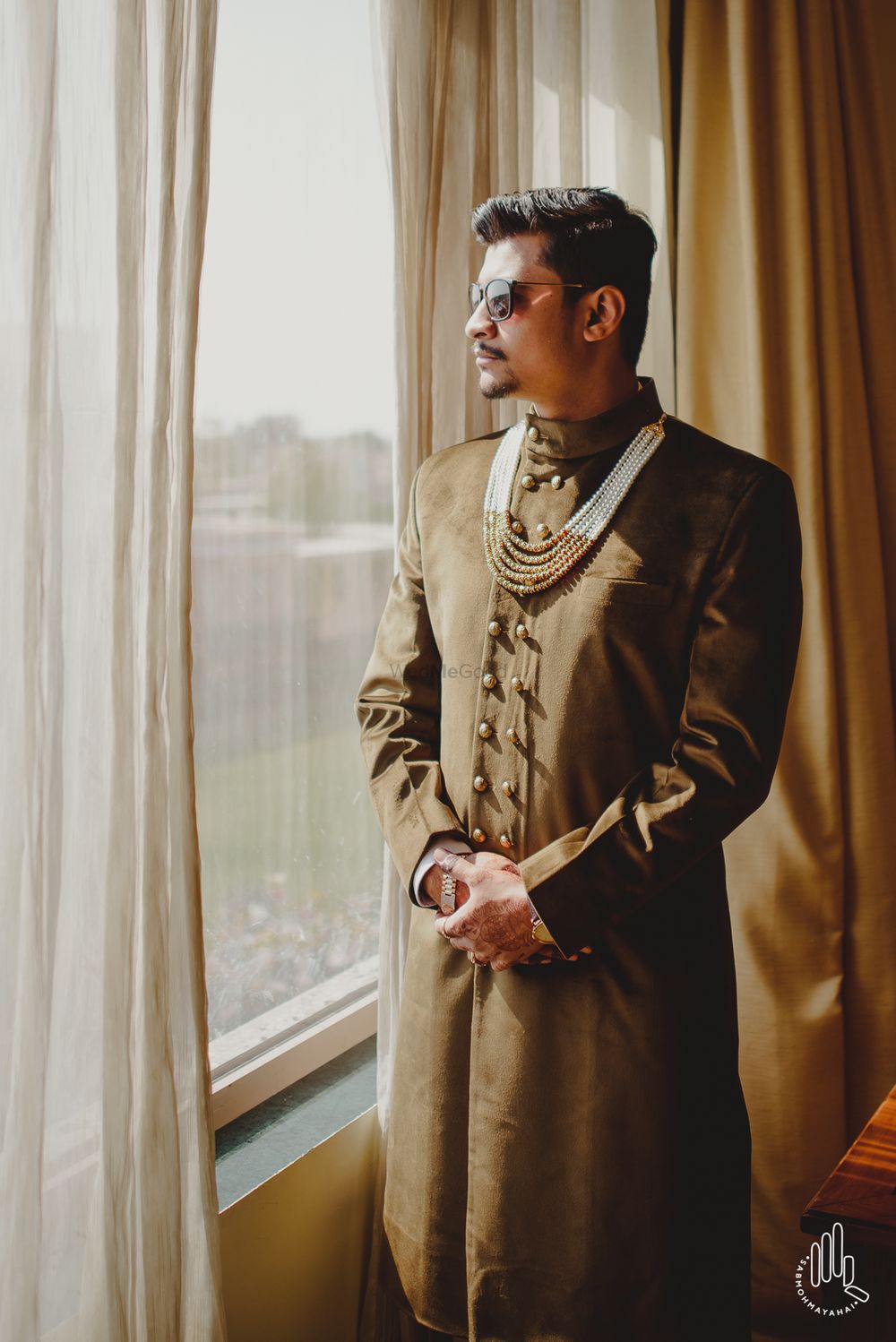 Photo of Groom in dull brown sherwani with double row of buttons and pearl necklace