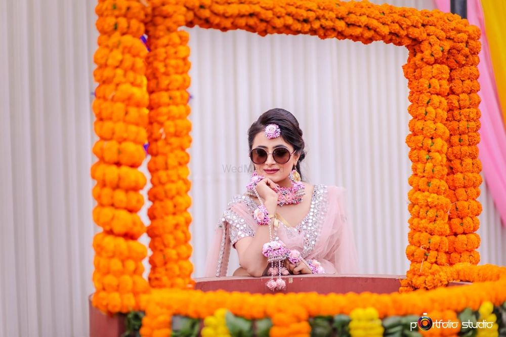 Photo of Bride on mehendi wearing sunglasses behind floral frame