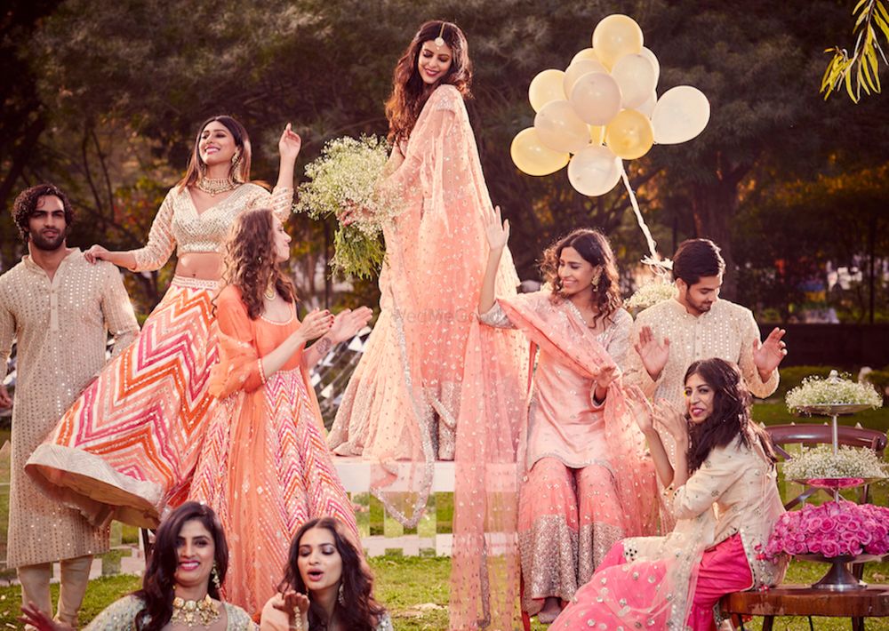 Photo of A bride and her bridesmaids in pastel outfits
