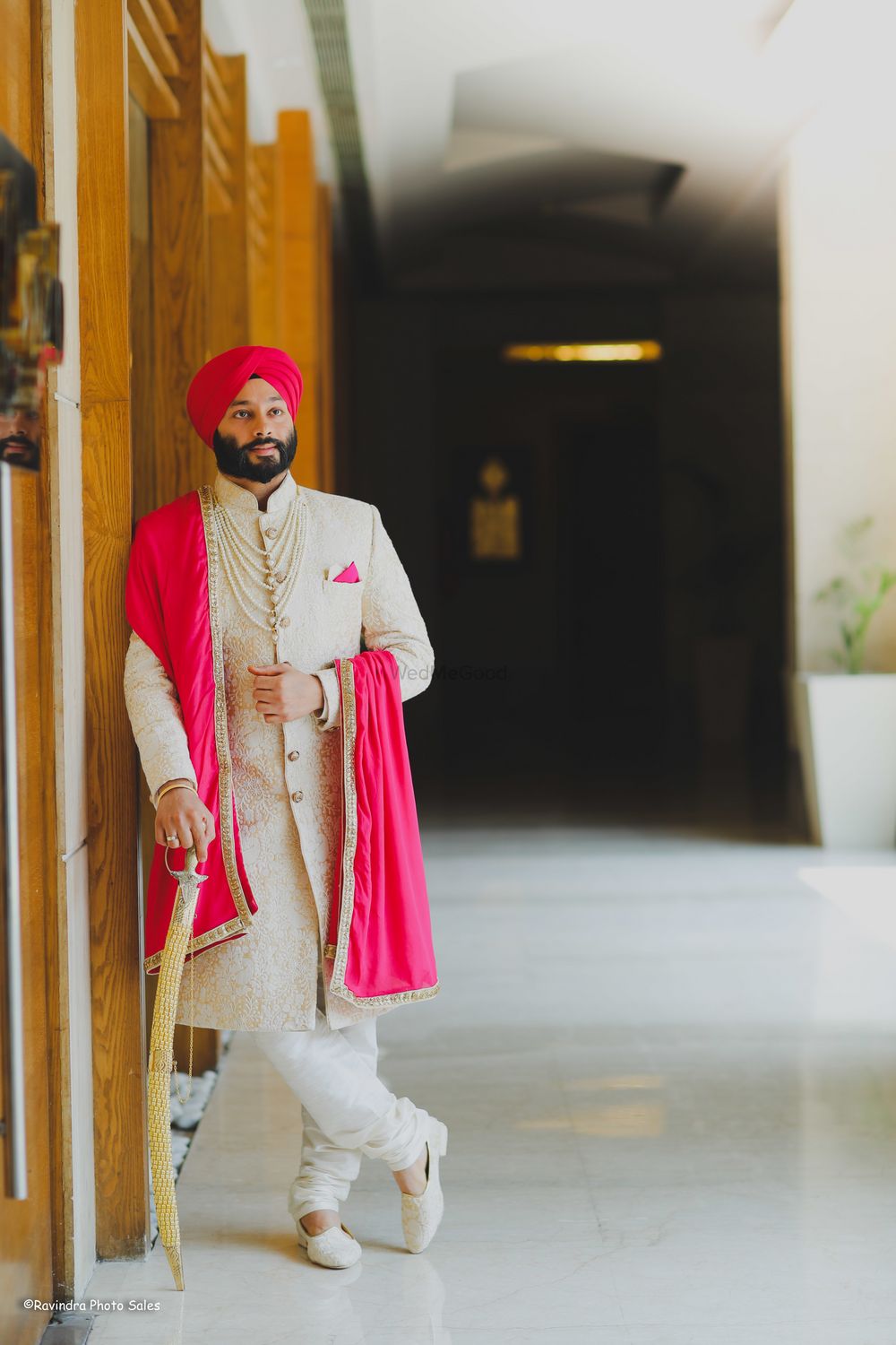 Photo of A groom in a stunning off-white embroidered sherwani coupled with bright pink dupatta and turban.