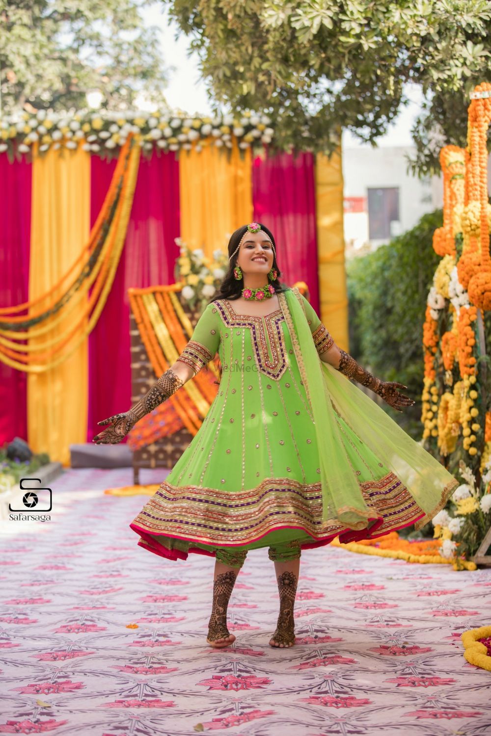 Photo of A bride in a green mehndi outfit twirling in happiness