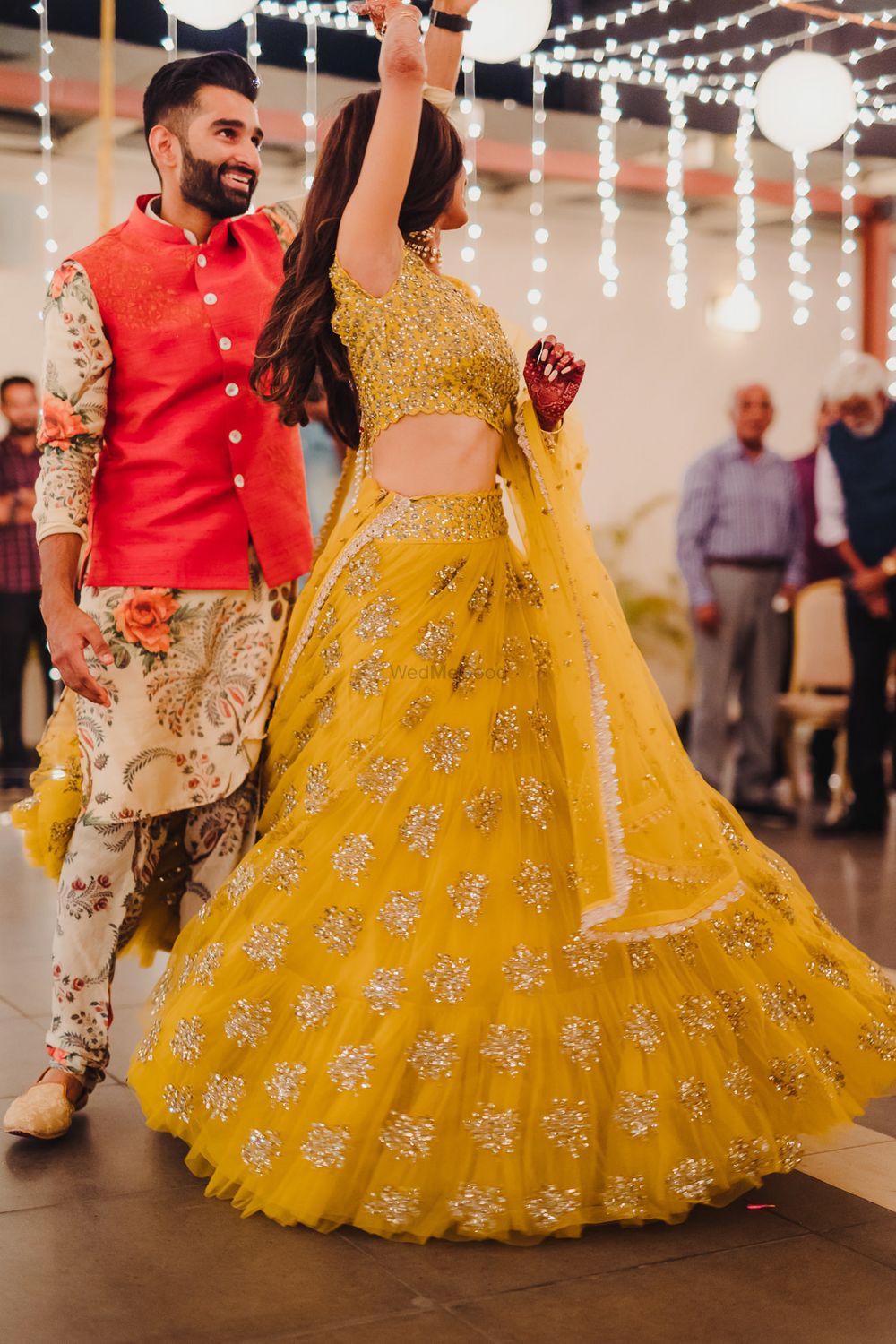 Photo of Dancing couple shot on sangeet with mustard yellow lehenga