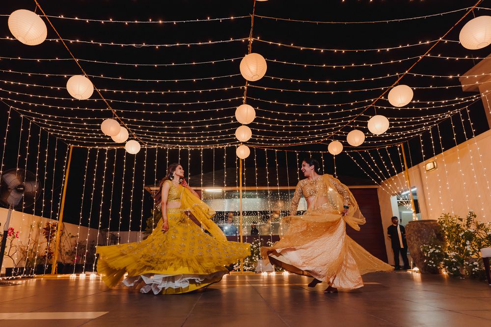 Photo of Bride and bridesmaid dancing in matching lehenga