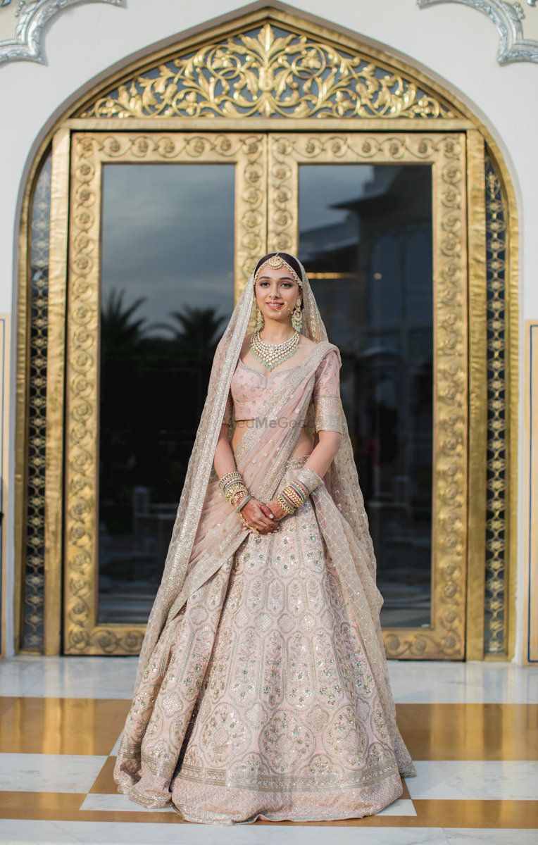 Photo of A bride in a blush pink lehenga on her wedding day