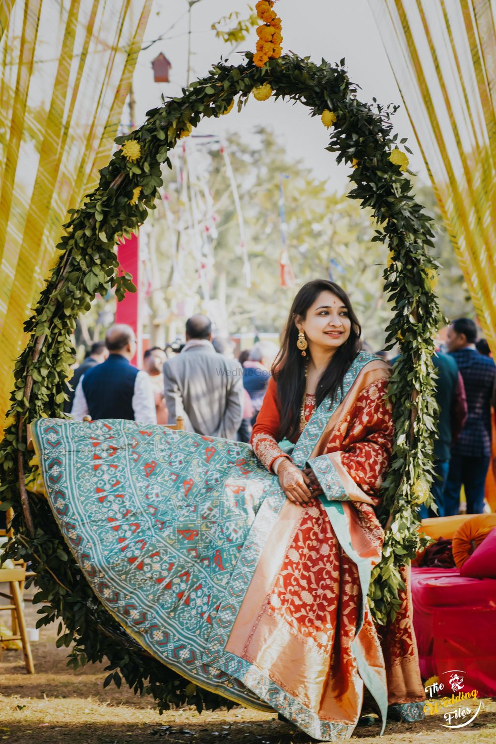 Photo of A to be bride sitting in a floral wreath at her mehndi
