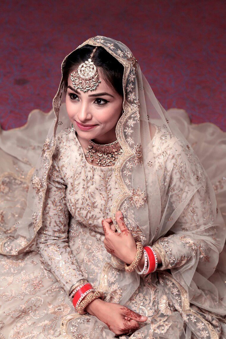Photo of A bride in a silver bridal lehenga and an oversized mangtikka