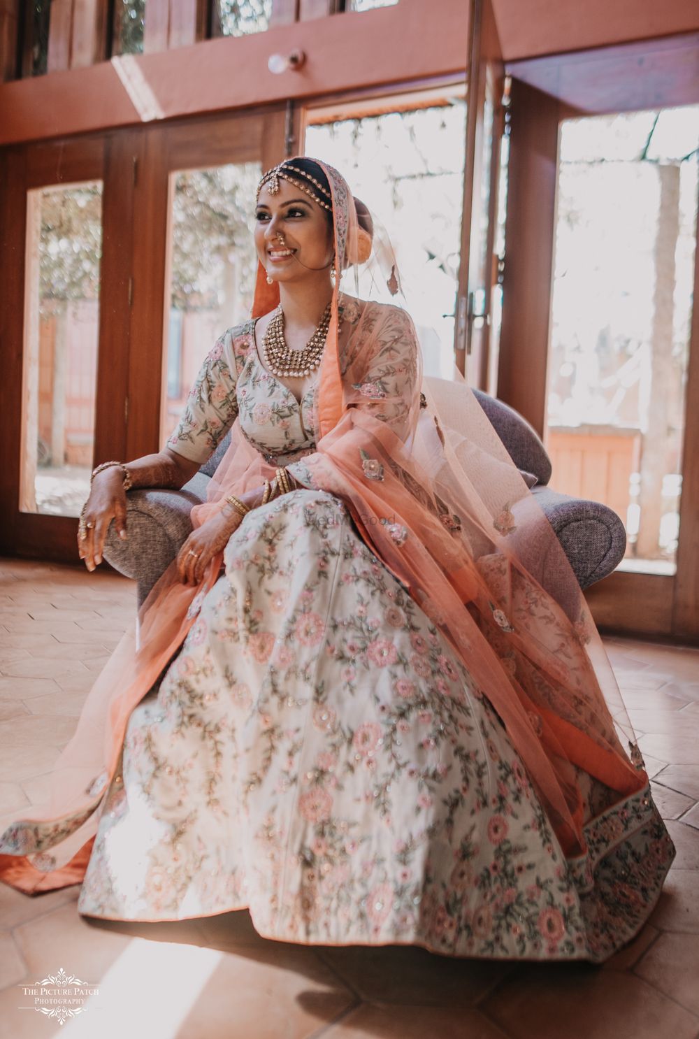 Photo of A bride in a white lehenga with floral embroidery with a peach dupatta