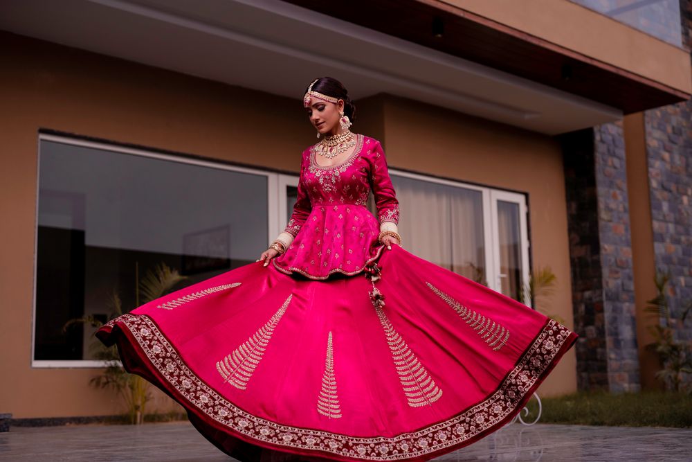 Photo of A bride in a red lehenga with peplum top wirling on her wedding day