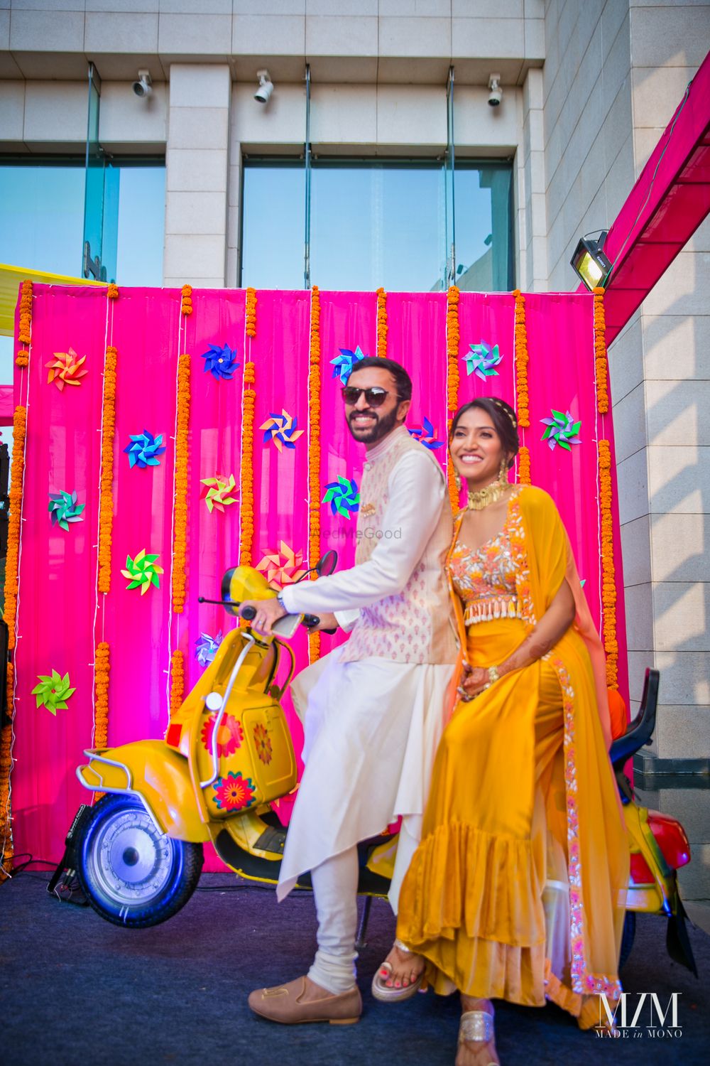 Photo of A bride and groom in coordinated outfits on their mehendi, posing with fun props