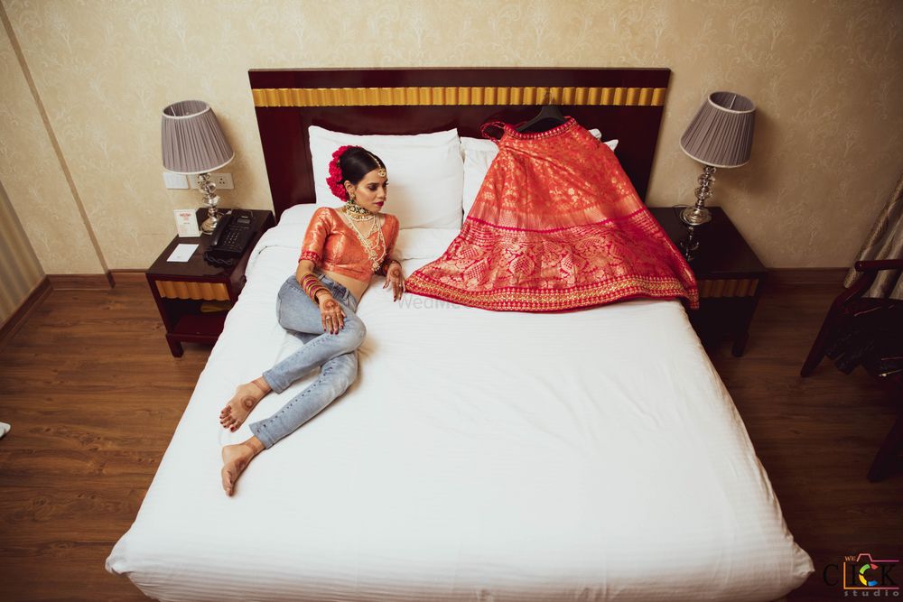 Photo of getting ready shot idea with bride and lehenga on the bed
