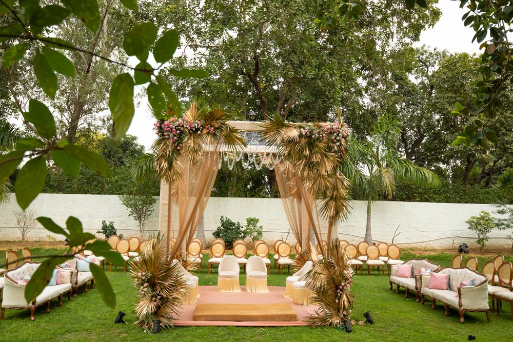 Photo of simple mandap decor in gold with palm leaves
