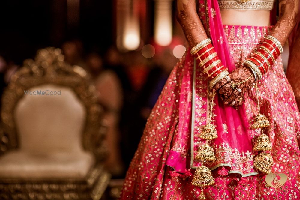 Photo of Bride in a heavy bright pink lehenga with chooda & gold kaleere.