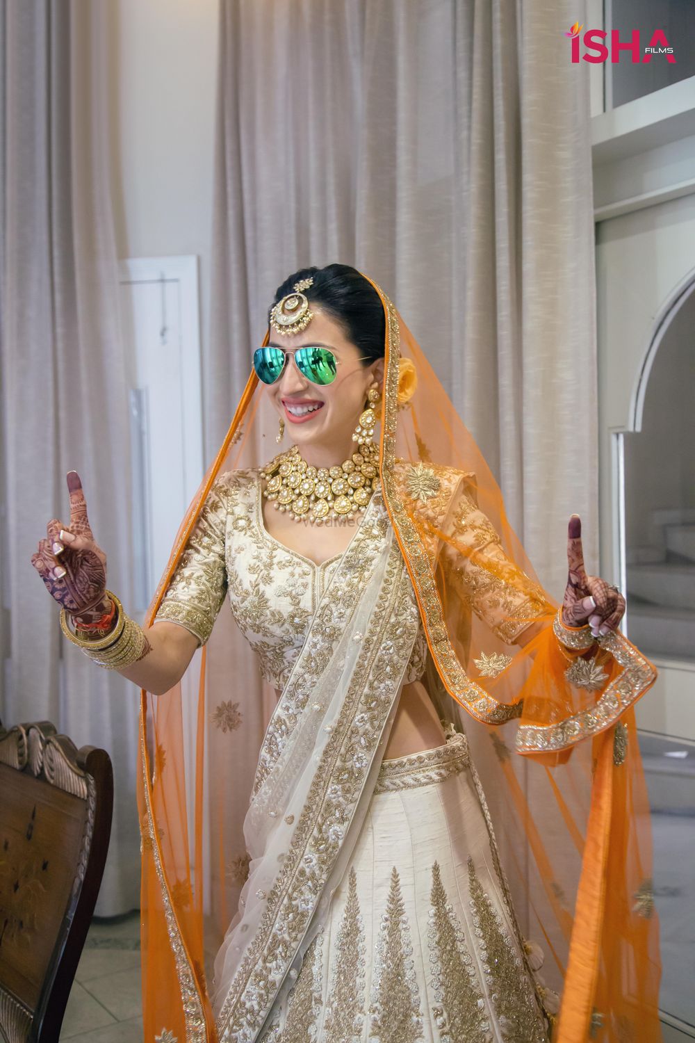 Photo of bride in ivory lehenga with a contrasting orange double dupatta