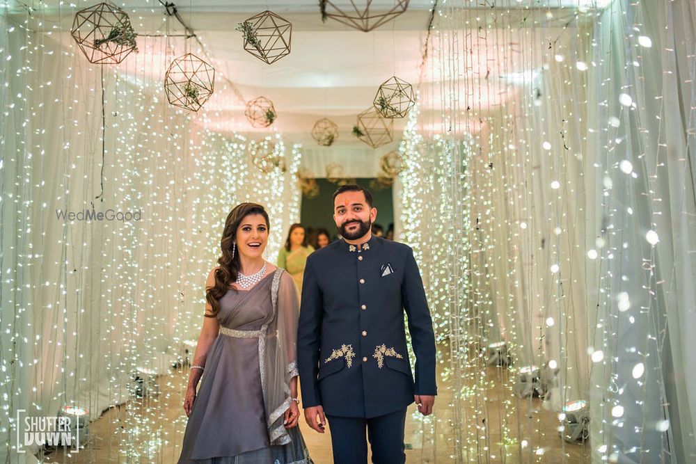 Photo of matching bride and groom entering cocktail with fairy lights