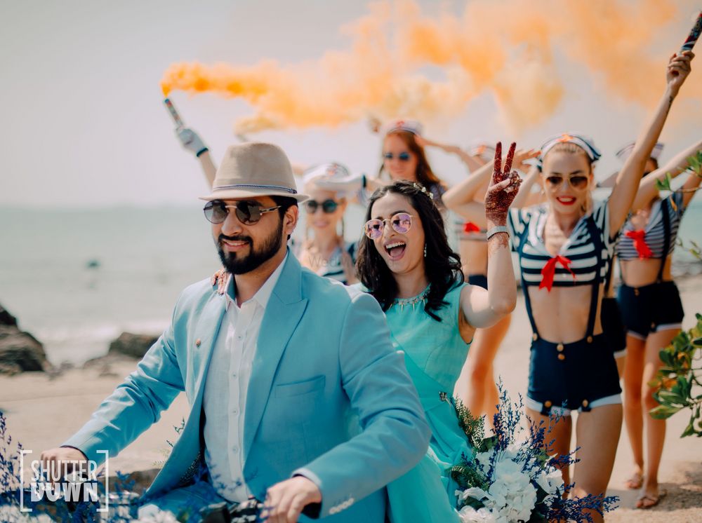 Photo of couple entry on bike with smoke sticks for beach wedding