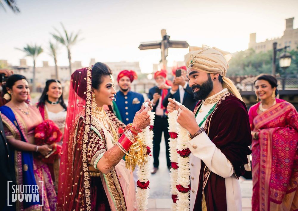 Photo of coordinated bride and groom jaimala shot in maroon