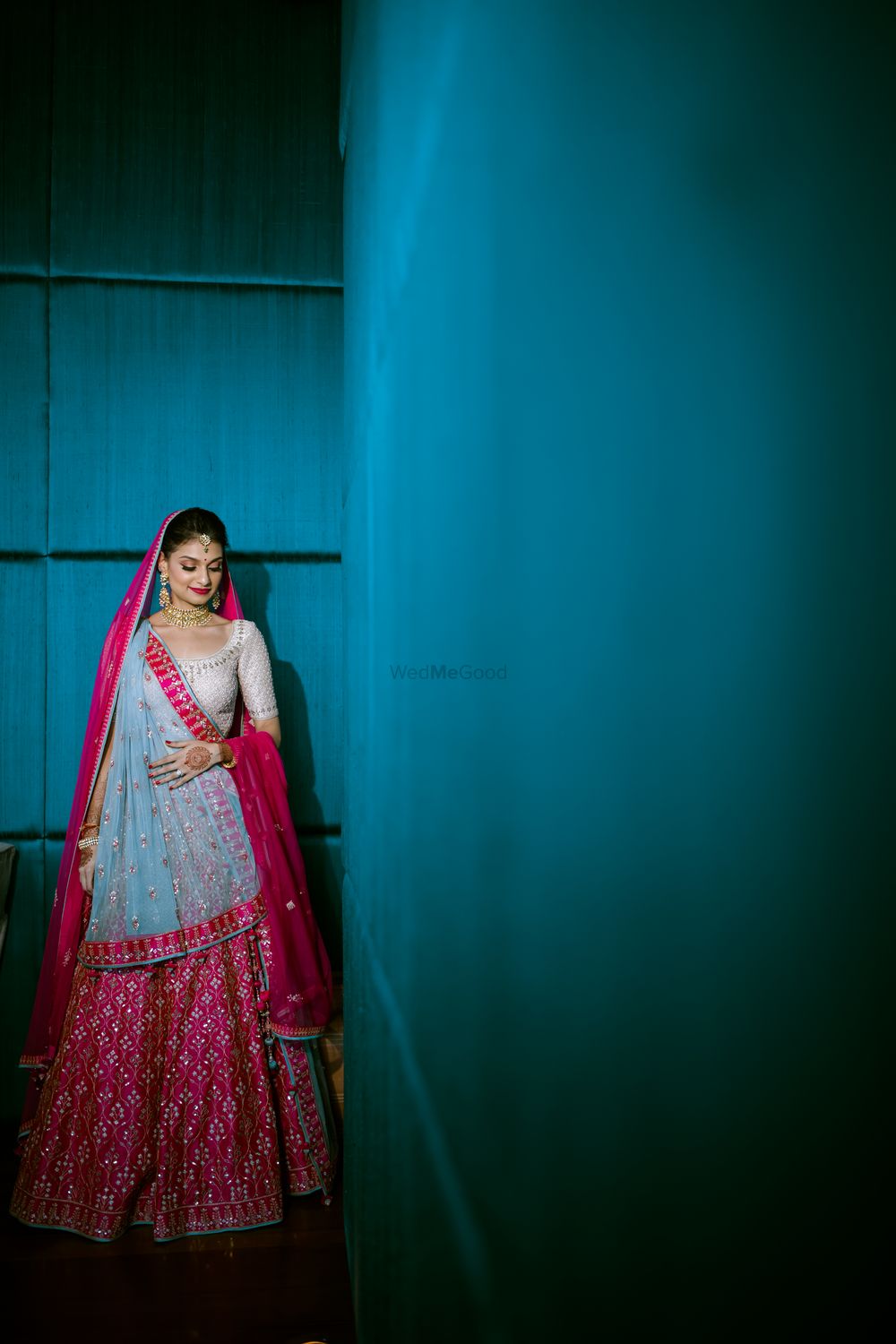 Photo of A bride in a pink lehenga with a contrasting blue dupatta on her wedding day