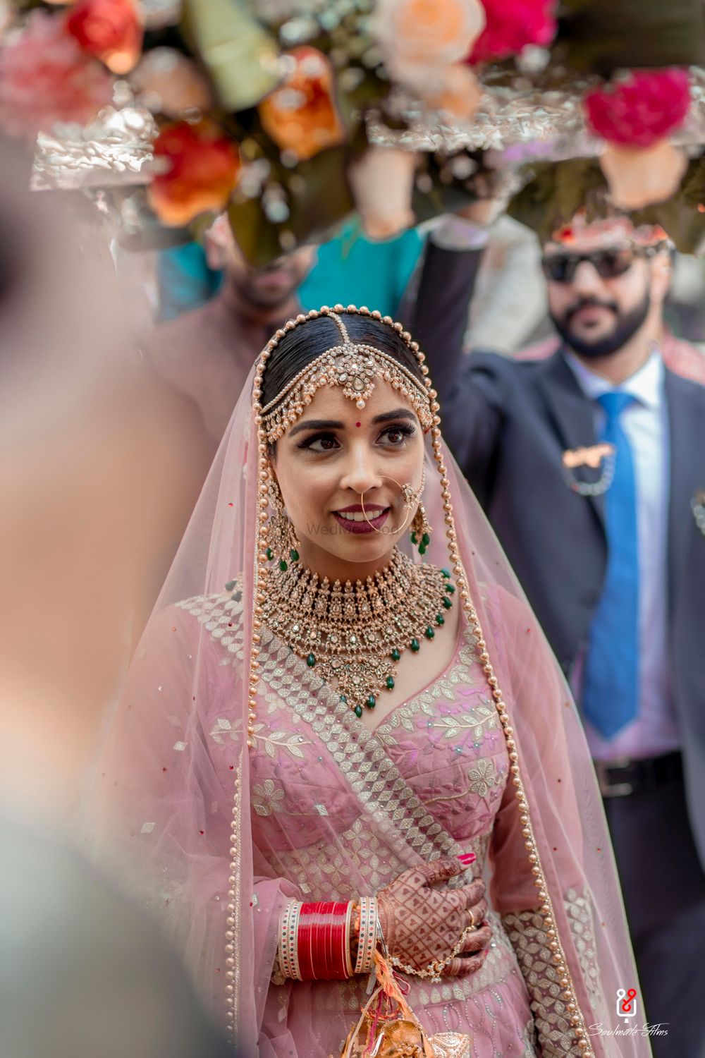 Photo of A bride in a light pink lehenga with gold and green jewellery