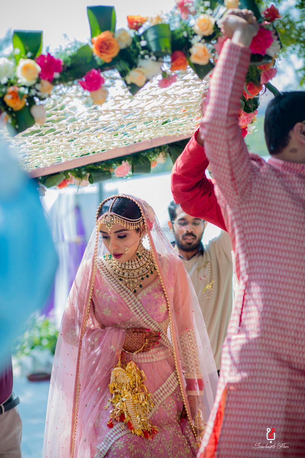 Photo of A bride in a light pink lehenga under a phoolon ki chaadar