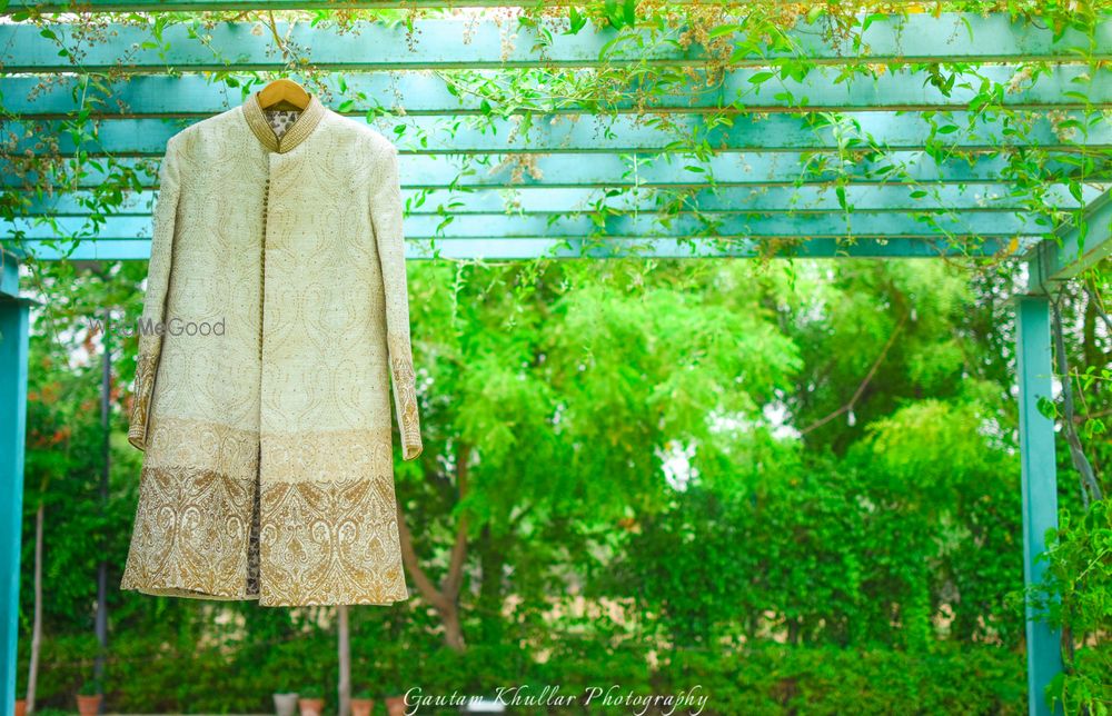 Photo of Cream Sherwani with Gold Border Work on a Hanger