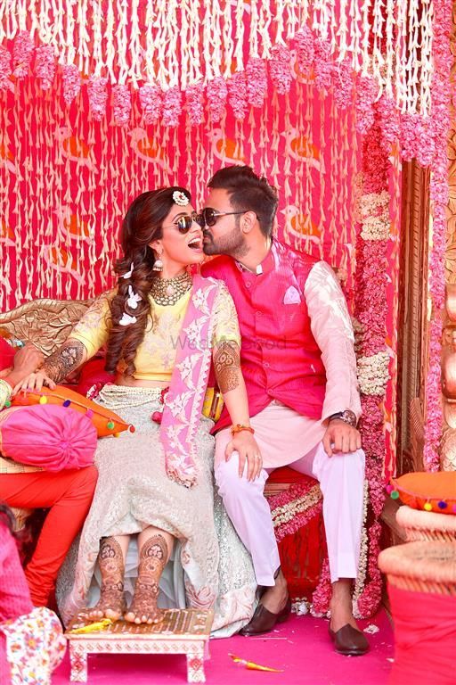 Photo of mehendi couple portrait with groom kissing the bride