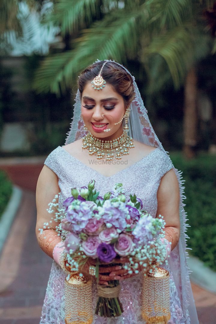 Photo of bride holding bouquet wearing lilac lehenga