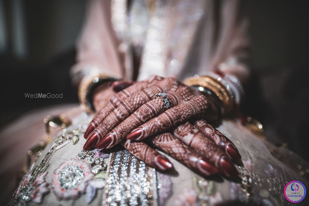 Photo of beautiful bridal hands with mehendi and maroon manicure