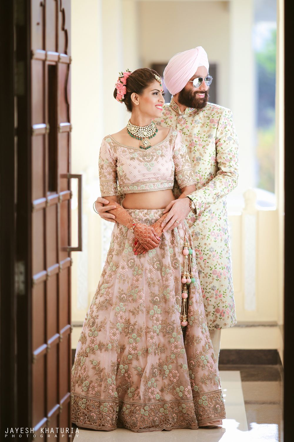 Photo of matching pastel bride and groom in embroidered outfits