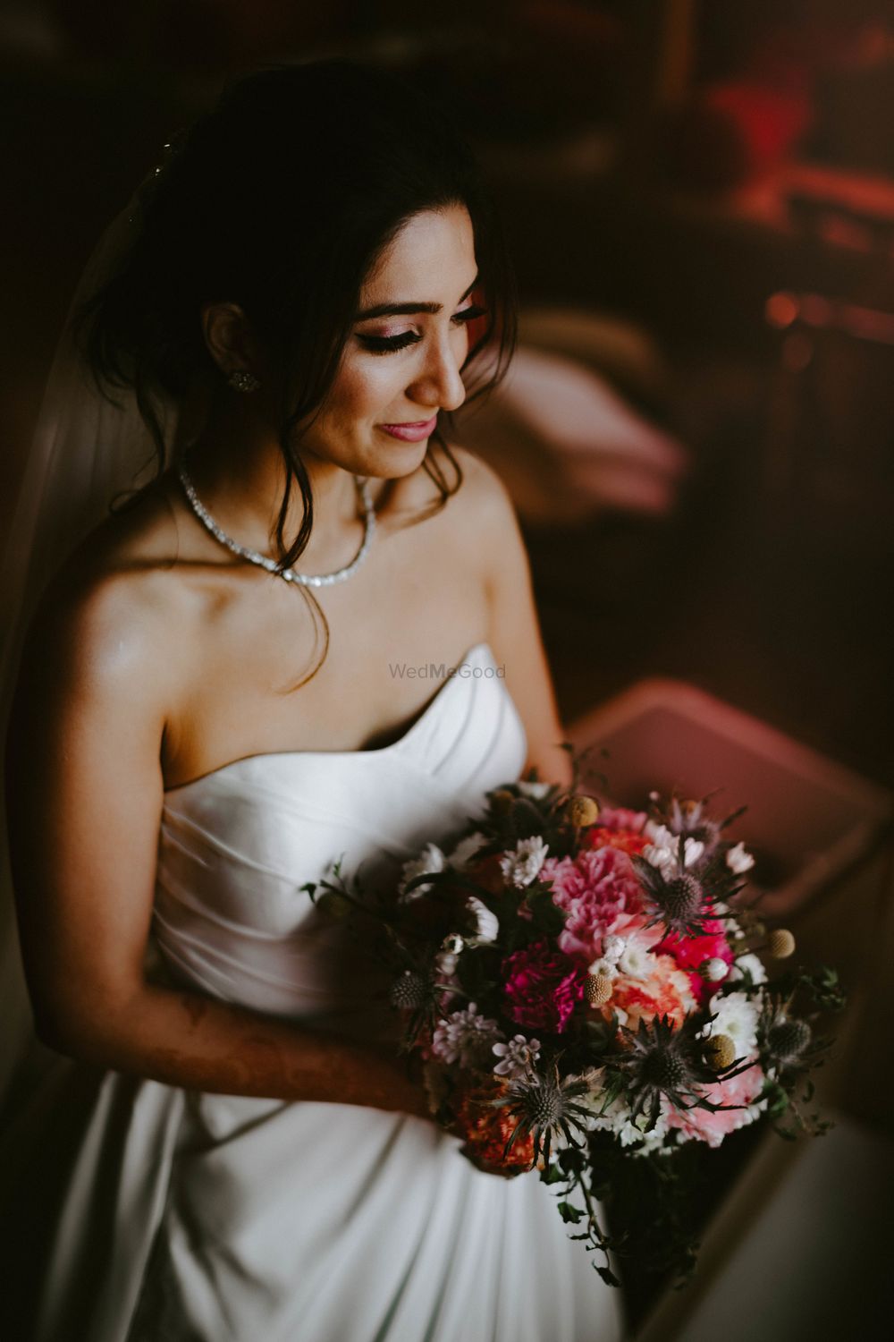 Photo of christian bride in strapless gown and red bouquet
