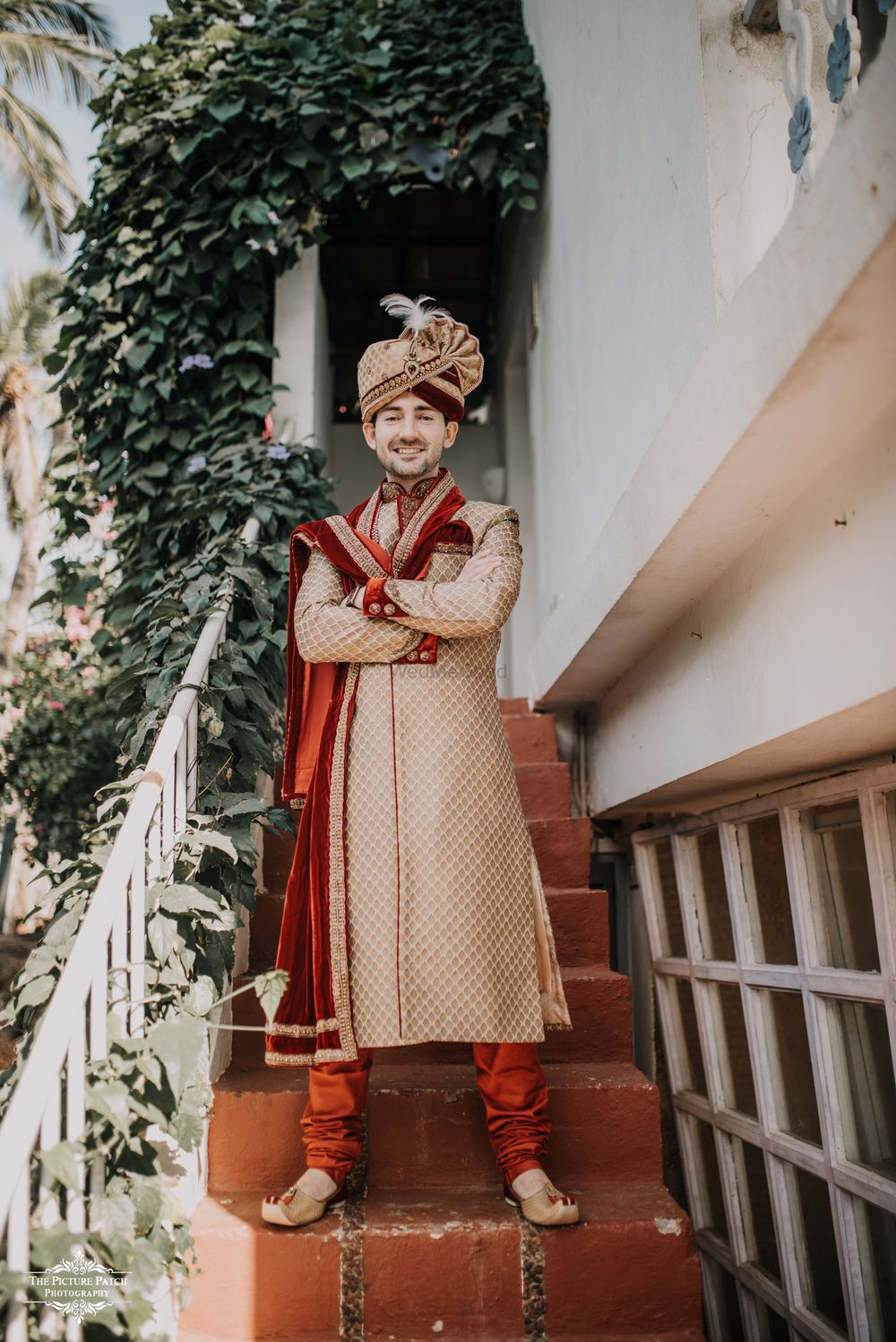 Photo of A groom in a gold sherwani with a maroon velvet stole.