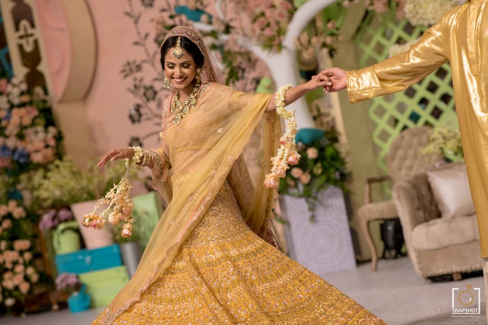 Photo of Twirling bride shot of a bride in a bright yellow golden lehenga