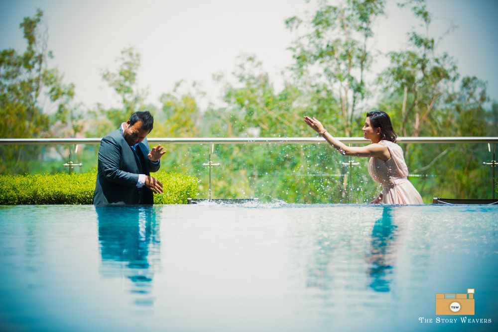 Photo of pre wedding shoot in swimming pool. bride and groom throwing water