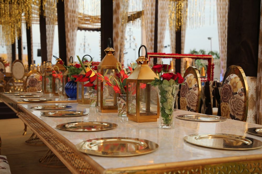 Photo of Table settings done with ornate centerpieces, hints of gold and some flowers.