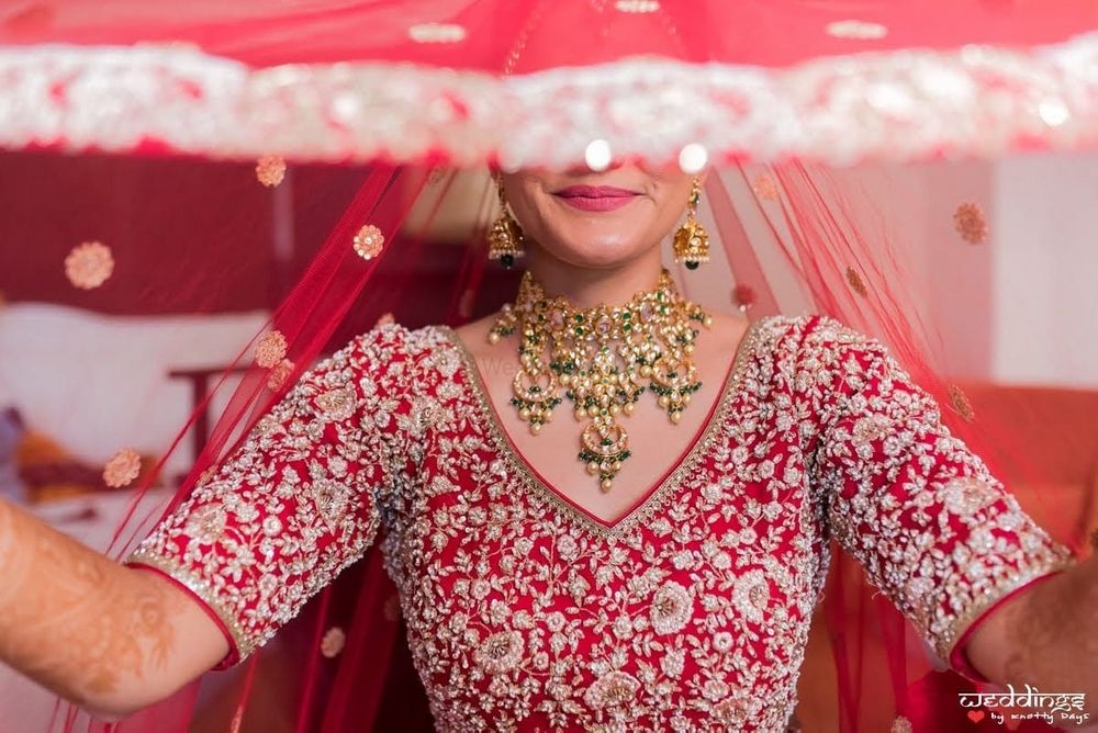 Photo of A beautiful veil shot of a bride dressed in red.
