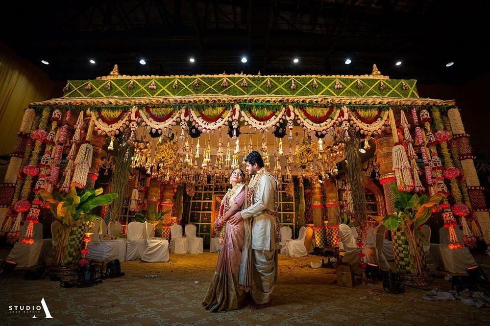 Photo of South Indian couple posing against a grand mandapam.
