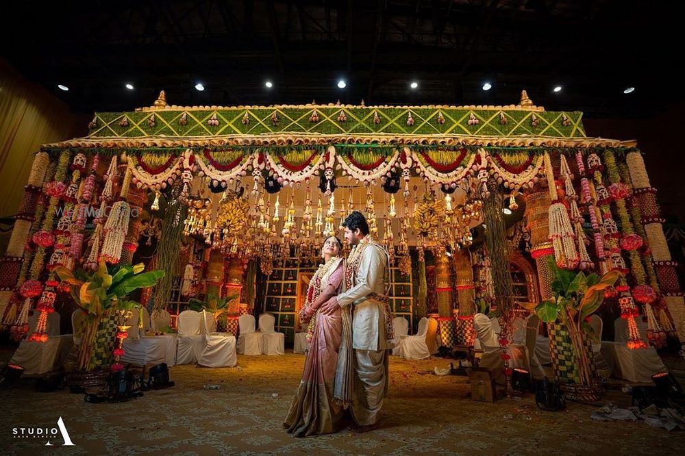 Photo of South Indian couple posing against a grand mandapam.