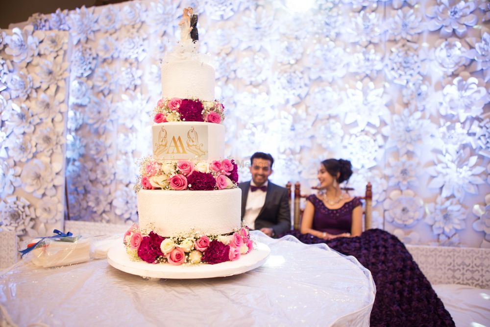Photo of Three-layered white wedding cake with flowers