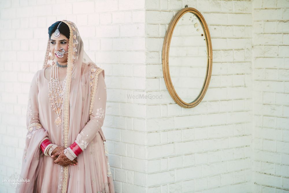 Photo of Bride in Pastel Pink Lehenga and Red and White Chooda