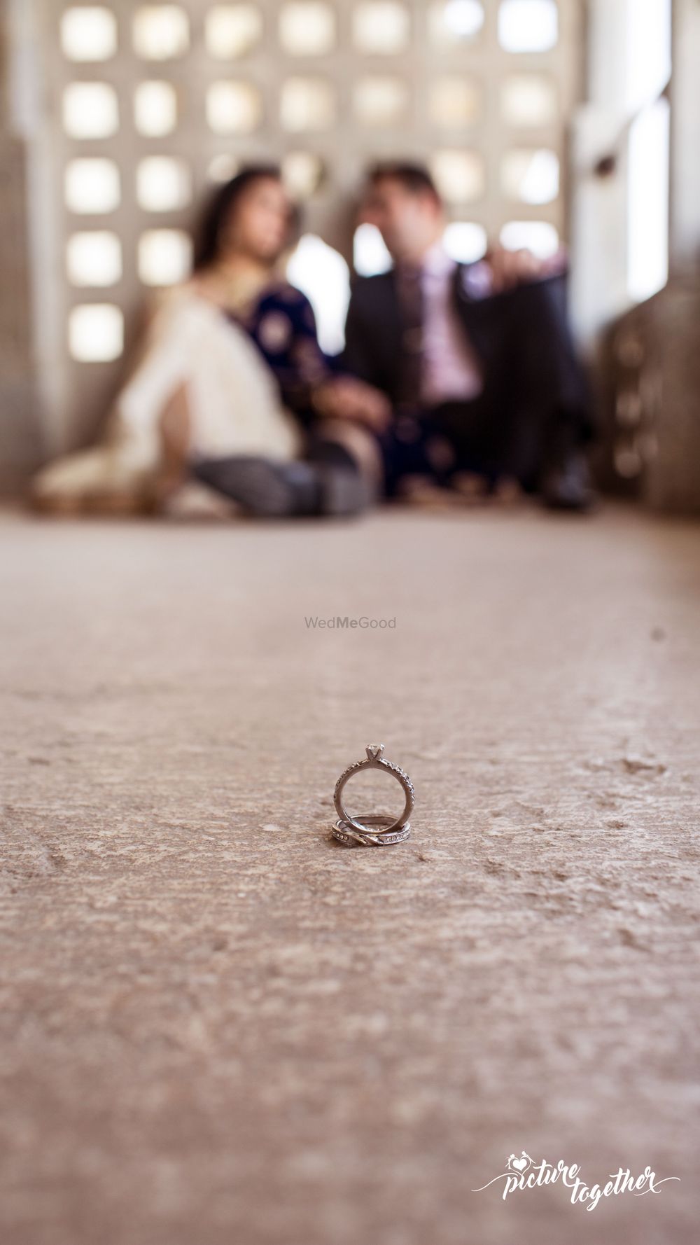 Photo of Engagement Rings in Focus with Couple Out of Focus