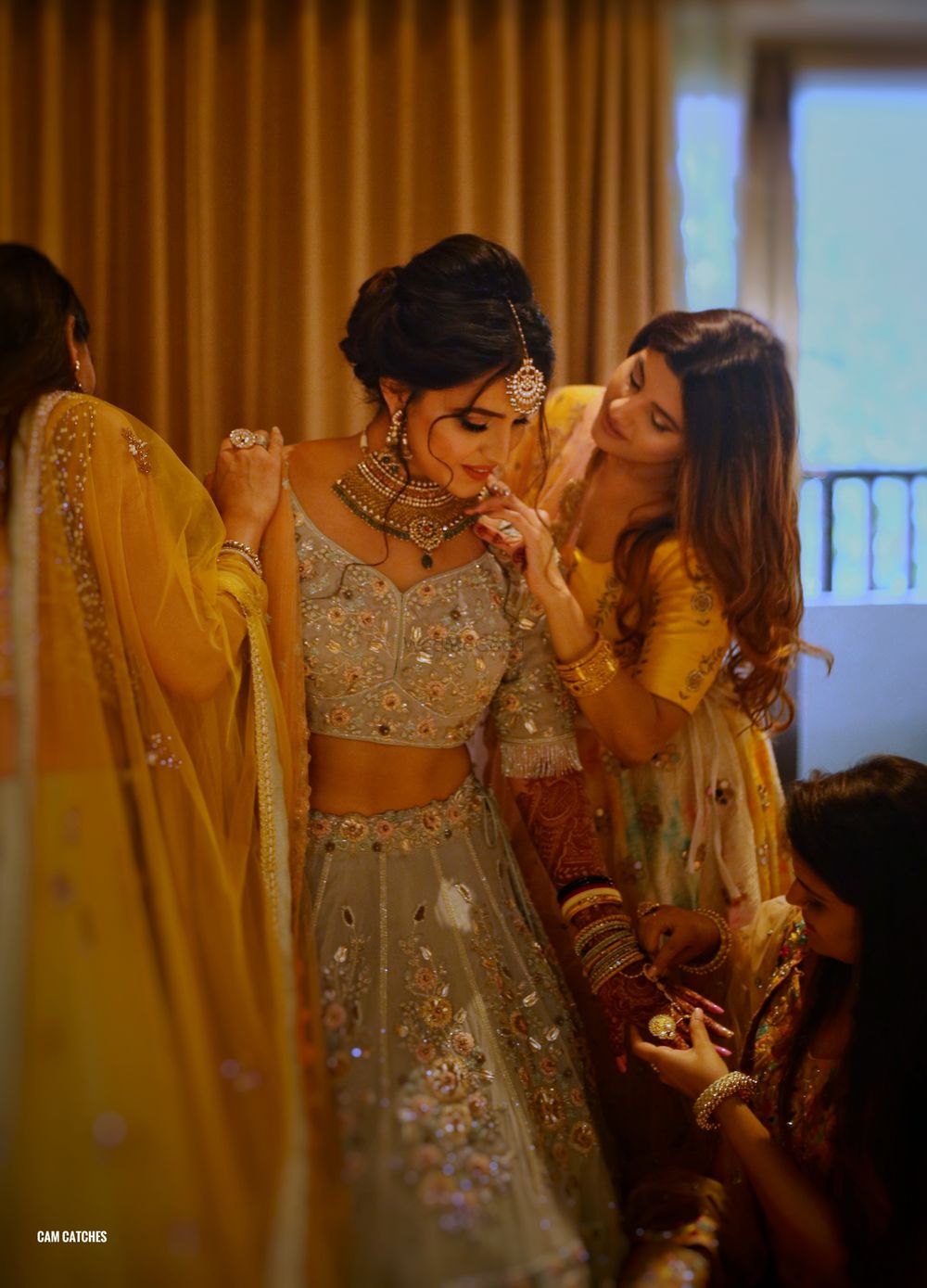 Photo of Bridesmaids helping bride in green lehenga get ready