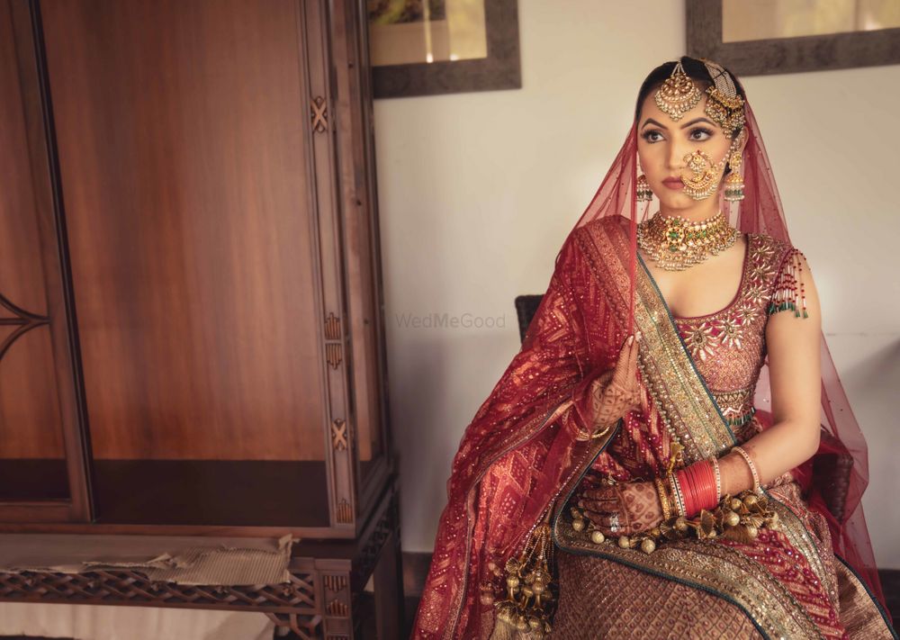 Photo of Candid shot of a bride in a red lehenga and vintage jewellery.