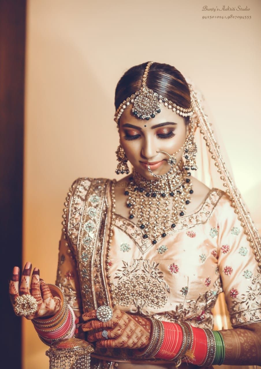 Photo of Candid shot of a bride dressed in a light pink lehenga with contrasting jewellery.