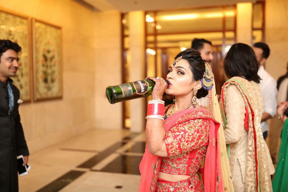 Photo of Bride in Red Posing with Whiskey Bottle