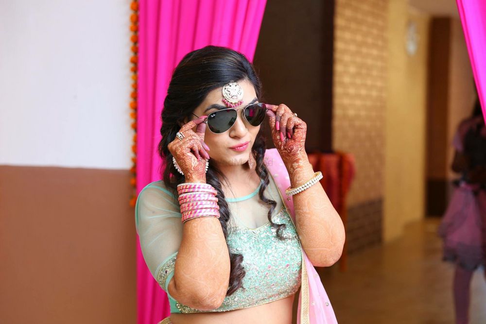Photo of Bride Posing with Sunglasses on Mehendi