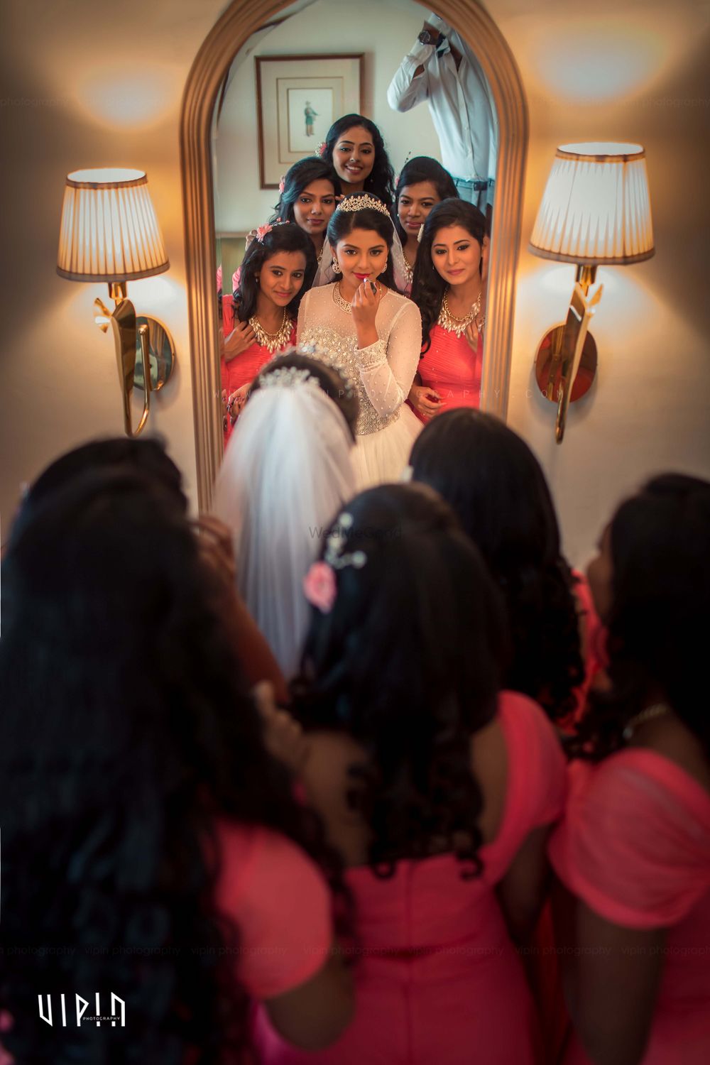 Photo of Christian Bride and Bridesmaids Looking into Mirror