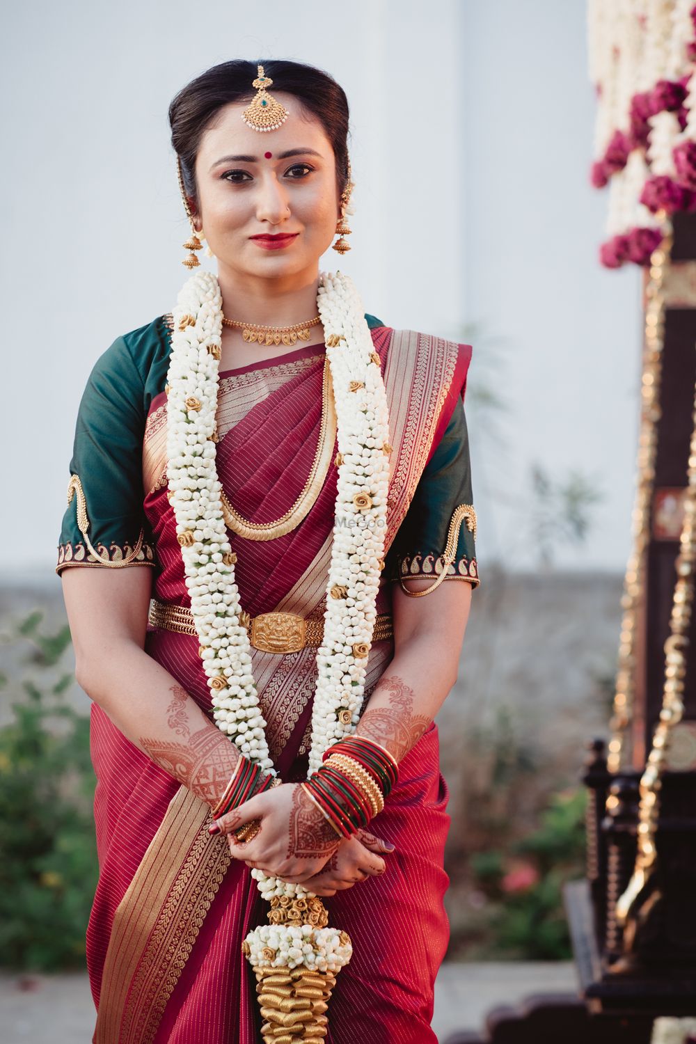 Photo of South Indian bride dressed in a maroon saree with a dark green blouse.