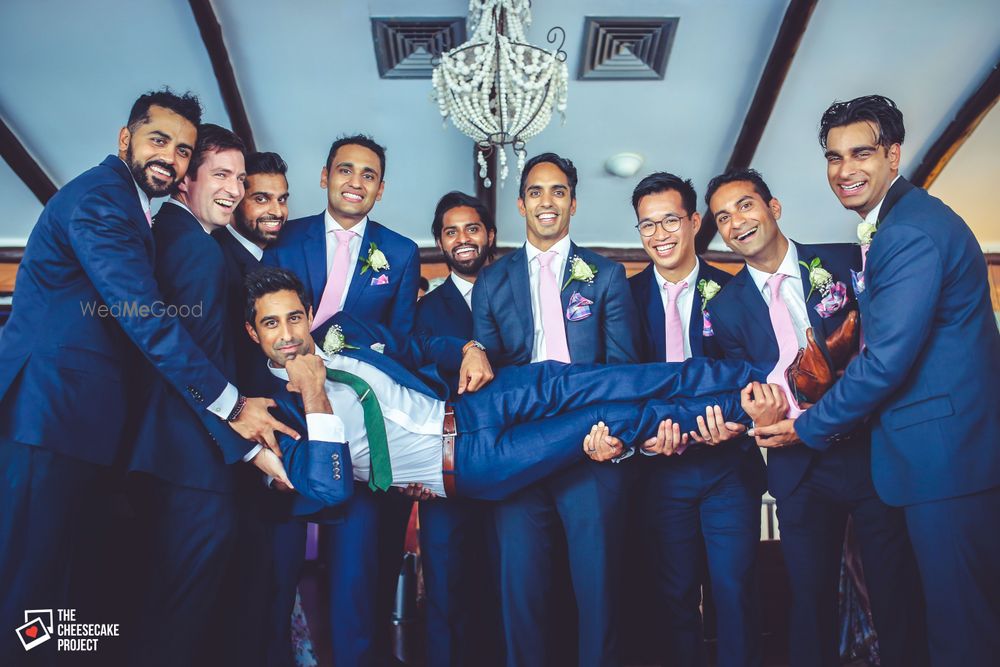 Photo of Matching Groomsmen in Grey Picking up Groom