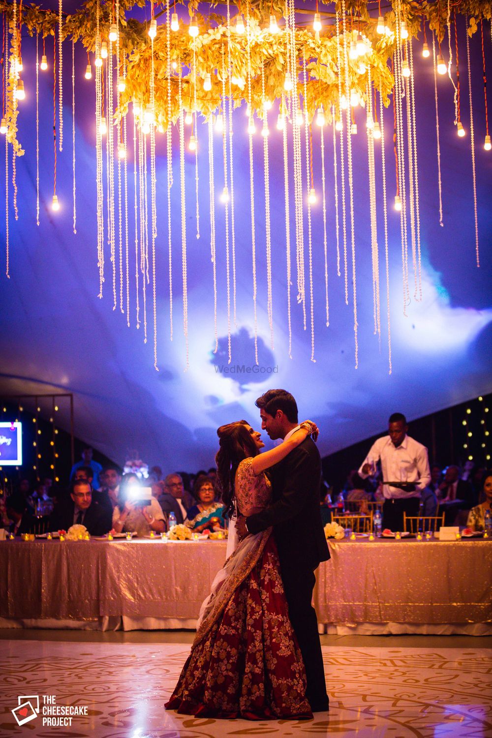Photo of Couple dancing under chandelier with fairy lights